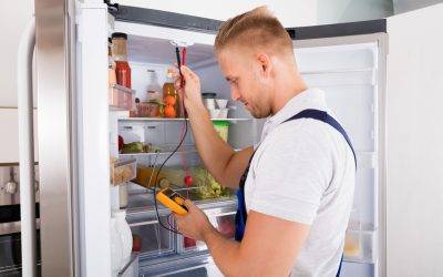 70823974 - young repairman checking refrigerator with digital multimeter